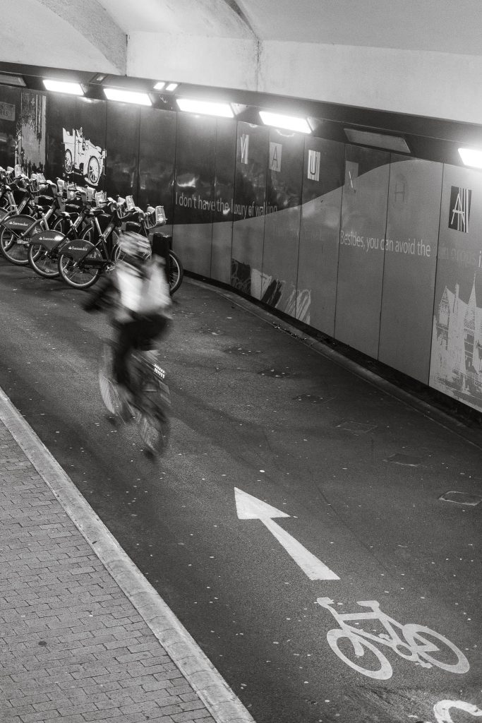 A cyclist passing through one of the railway arches at London Vauxhall with rows of bikes visible in the background