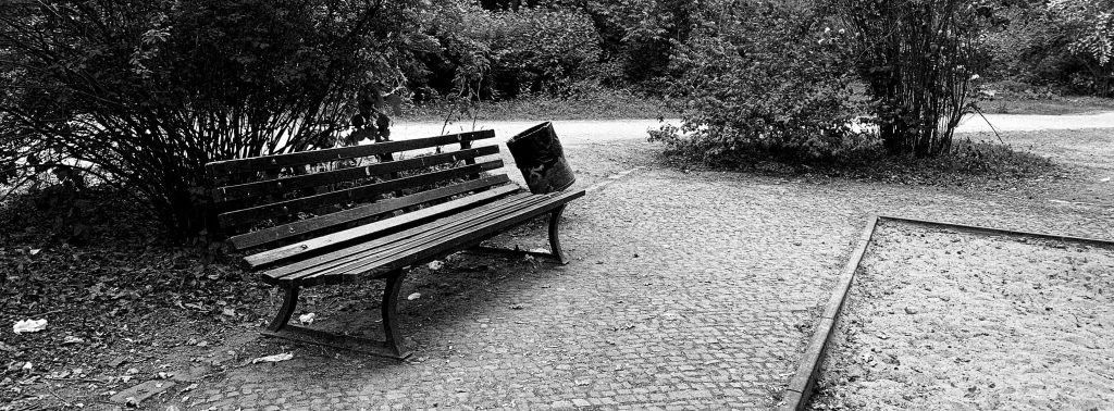 A black and white photo of a wooden park bench in Tiergarten park in Berlin